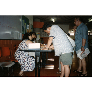 Man signs in at a welcome table during a Chinese Resident Association meeting