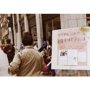 Community members attempt to distribute handouts and collect signatures on the corner of Beach Street and Harrison Avenue on behalf of Long Guang Huang