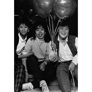 Three students sit with balloons at the Ell Student Center 20th anniversary