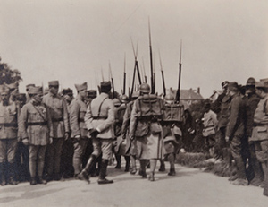 Street-level view of soldiers in full kit marching away from the camera between crowds of soldiers on either side