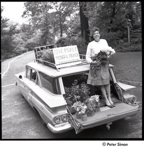 Andrea Simon: in car, holding flowers in front of sign that reads, 'Riverdale Mental Health Association'