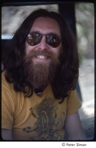 Krishna Das sitting inside a car and smiling