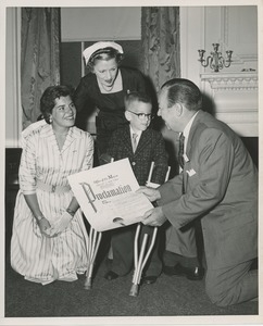 Mayor Robert F. Wagner presenting a proclamation from the American theatre wing to a young boy with forearm crutches