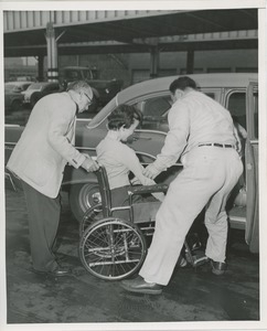 Women in wheelchair helped into car