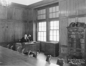 Suffolk University President Gleason L. Archer (1906-1948) seated at desk in the Archer Building (20 Derne Street)