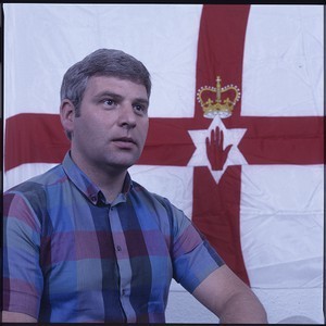 John McMichael, former leader of the UDA, later killed by a bomb placed under his car by the PIRA. Portraits of him in front of the Ulster flag