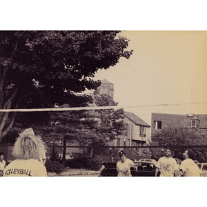 View of a volleyball net and players, with Villa Victoria housing in the background.