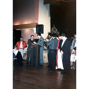 Group of men gathered at the front of the hall to accept of present an award during a community Christmas celebration at the Jorge Hernandez Cultural Center.