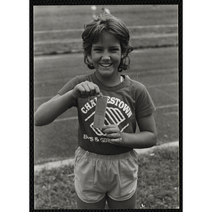 A track winner, wearing a Charlestown Boys & Girls Club t-shirt, displays his award ribbon,