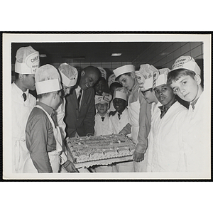Members of the Tom Pappas Chefs' Club and an unidentified man pose with a large decorated cake