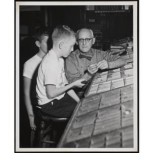 Two boys receive a typesetting tutorial from a printer