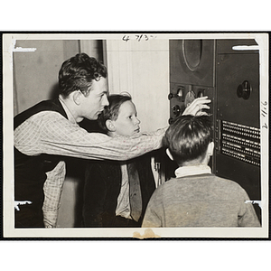 A man provides a tutorial for two boys on operating a shortwave radio