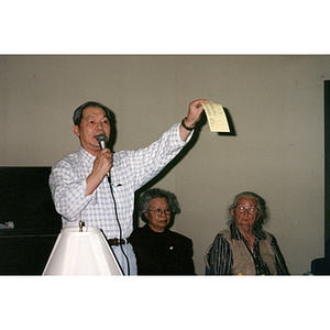 Man addresses a room of people gathered for a Chinese Resident Association meeting