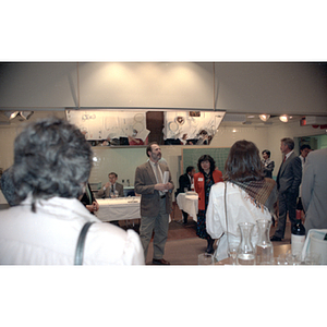 Man standing next to Charlene Tse addresses standing onlookers at a food tasting event