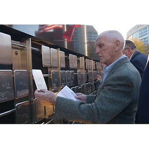 A man holds and reads a plaque on the Veterans Memorial at the dedication ceremony