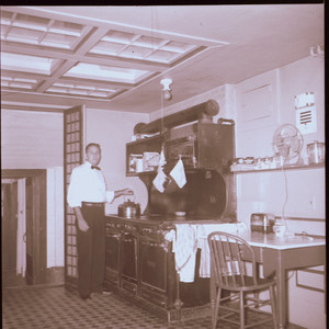 Man putting kettle on stove, kitchen, Beauport, Sleeper-McCann House, Gloucester, Mass.