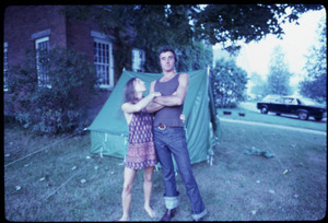 Woman and man standing in front of a tent pitched on the lawn of a house