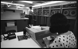 Woman entering data into a console as man mounts a tape on a Honeywell Model 400 mainframe computer