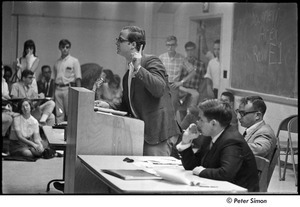 National Student Association Congress: man speaking at podium, Allard Lowenstein seated on right, wearing light suit