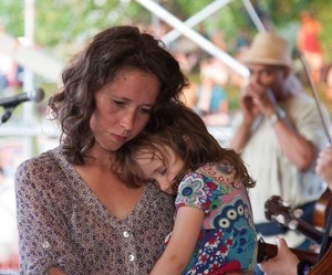 Sarah Lee Guthrie with young girl on her shoulder at the Clearwater Festival (Pete Seeger in background)