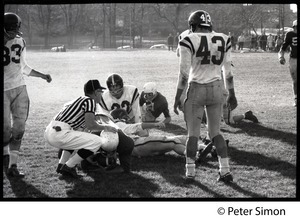 Referee kneeling over an injured football player while others look on