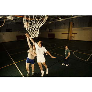 Players trying to shoot a basketball through a hoop