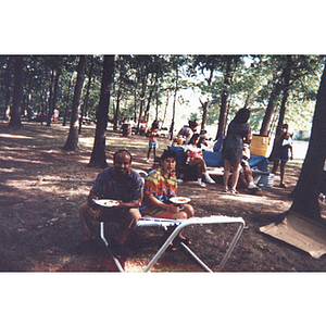 A man and woman sit together on a hammock during a picnic event