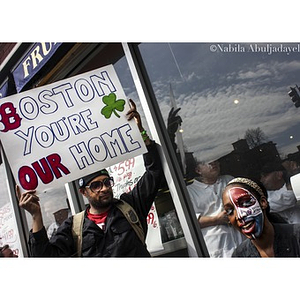 Man holding "Boston You're Our Home" sign alongside other spectators