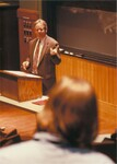 Suffolk University Professor Robert J. Allison (CAS) lecturing behind podium in classroom, photograph, circa 1990s