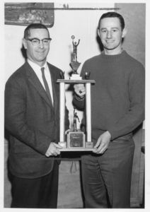 Suffolk University Athletics Director Charlie Law and student holding a basketball trophy, 1973