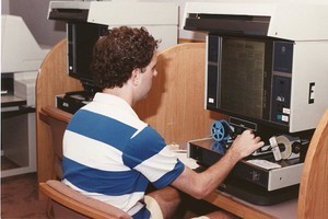 O'Neill Library interior: student using microfilm machine to view the Wall Street Journal