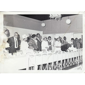 People stand at a long banquet table