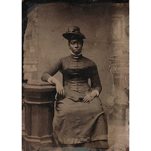 An African American woman sitting by a pedestal