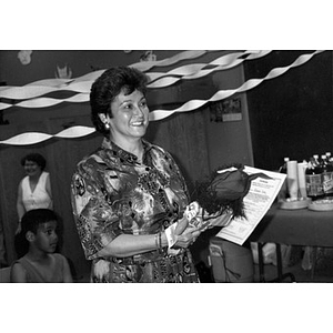 Woman holding a cloth doll and a certificate during a Child Care training program.
