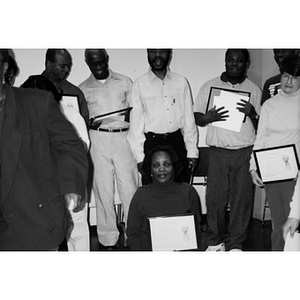 Group of people posing with framed certificates.