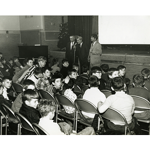"Captain Paul Sullivan (center) addressing South Boston juniors at Kiwanis sponsored X mas party" with Secretary George Mann (left) and Clubhouse Director Ronald D. Young (right)