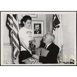 A man presents an award to a boy wearing a Boys' Clubs of Boston t-shirt