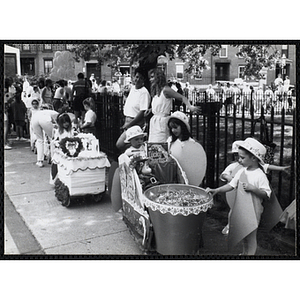 Children stand with miniature floats at a carnival