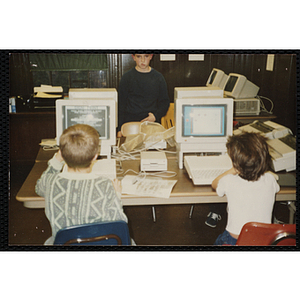 Two boys use Macintosh computers in a lab