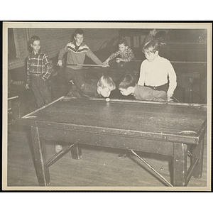 Two boys blowing on a billiard ball