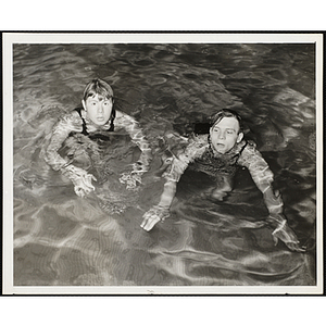 Two teenage boys wade in a pool