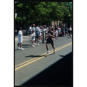 A woman runs past spectators during the Battle of Bunker Hill Road Race