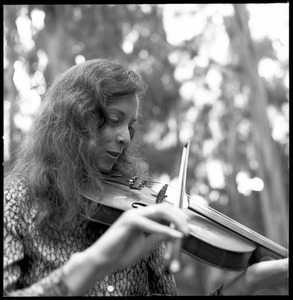 Woman playing a fiddle in a eucalyptus grove