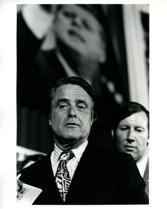 Sargent Shriver in front of post of John F. Kennedy