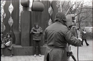 Richard Safft reading copy of Free Spirit Press magazine in front of sculpture during interview by Channel 5 news