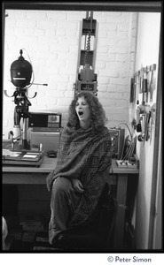 Usha (Cathy Brown) seated in a darkroom, yawning