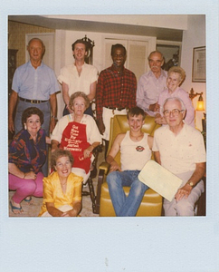 A Photograph of Marsha P. Johnson Posing with a Group in a Living Room, Wearing a Red Flannel and White Pants