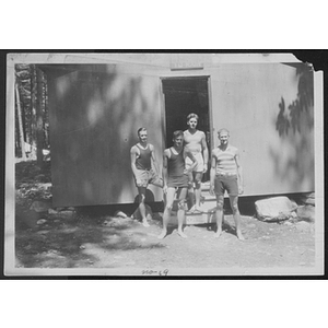 Four young men standing outside a cabin
