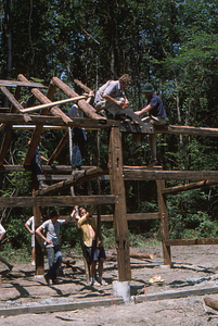 Henry Art and Lauren Stevens (top left to right) work on adjusting the Moon Barn rafters at the 2 August 1975 barn raising.