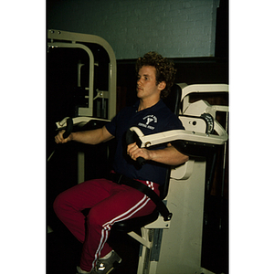 Man exercises his arms with an weightlifting machine